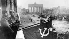 Soldados rusos muestran una bandera de la URSS delante de la Puerta de Brandenburgo, poco después de culminar la toma de la ciudad.