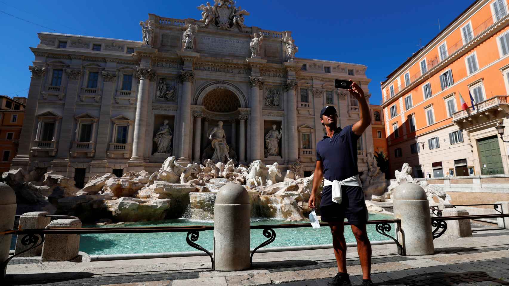 Un hombre sin mascarilla hace un selfie junto a la Fontana de Trevi, en Roma.