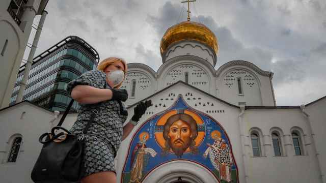 Una mujer con mascarilla frente a una iglesia ortodoxa de Moscú