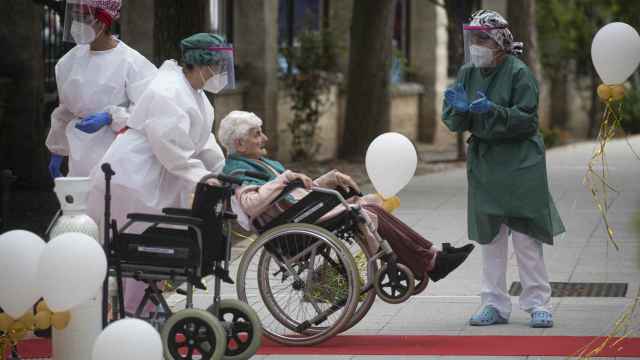 Una anciana en silla de ruedas conducida por personal sanitario a su llegada a la residencia La Pasionaria.
