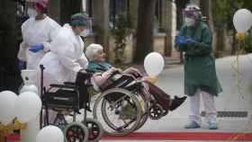 Una anciana en silla de ruedas conducida por personal sanitario a su llegada a la residencia La Pasionaria.