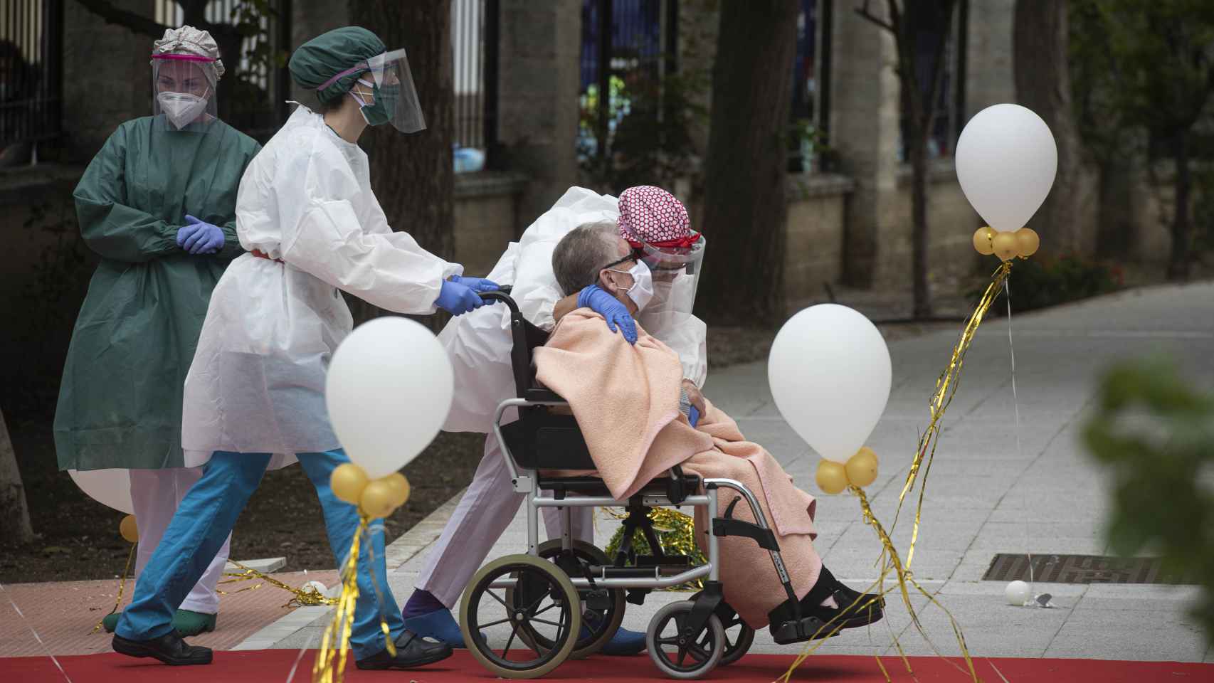 Una anciana en silla de ruedas recibe el cariño del personal sanitario a su llegada a la residencia La Pasionaria.