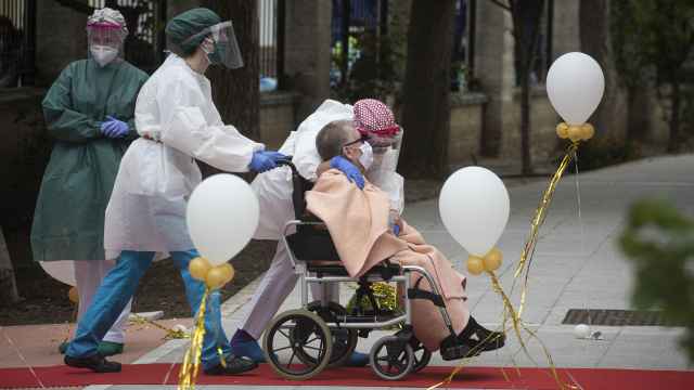 Una anciana en silla de ruedas recibe el cariño del personal sanitario en una residencia.
