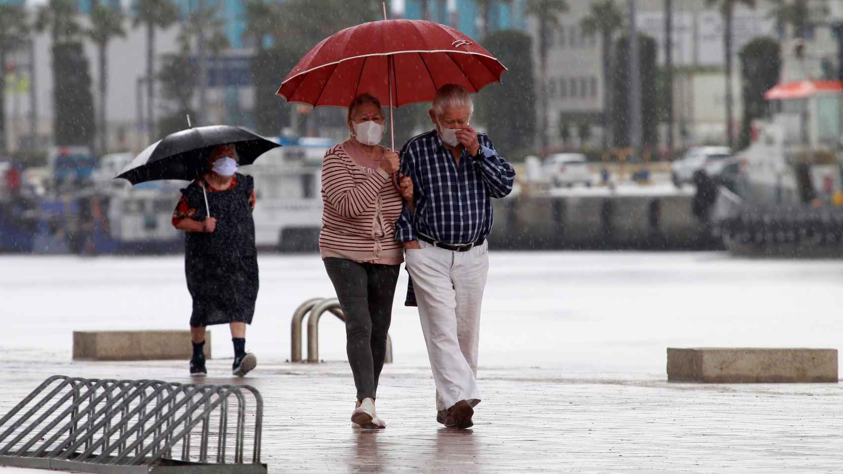 Una pareja en el paseo marítimo de Algeciras, bajo una intensa lluvia este domingo 10 de mayo.