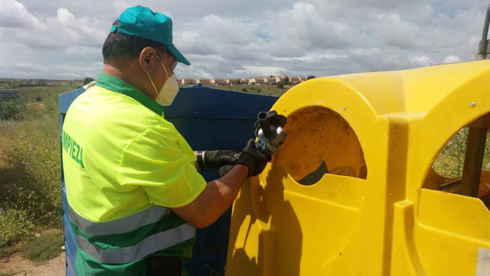 Un operario del Ayuntamiento de Toledo amplía la boca de uno de los contenedores