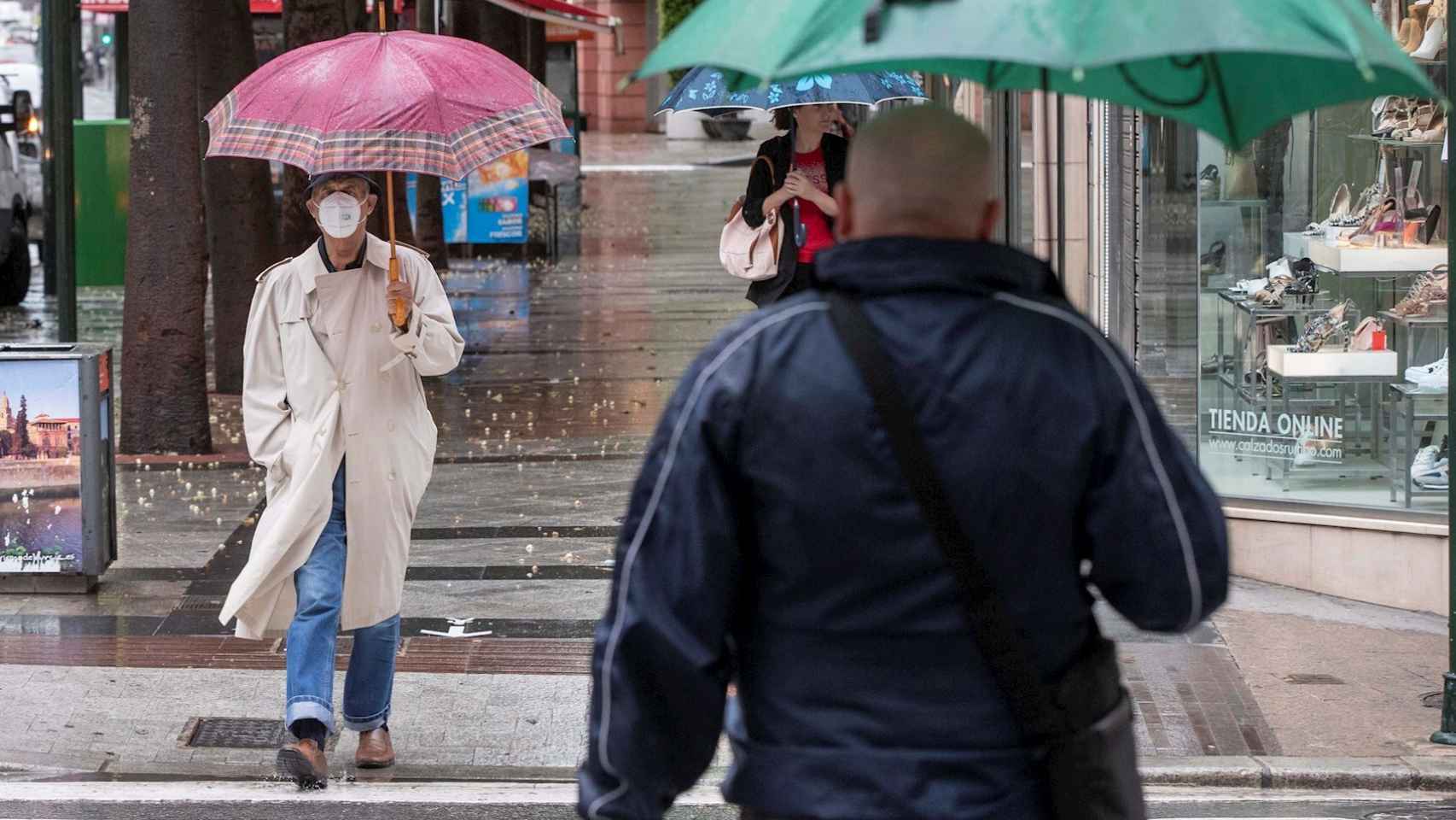 Varias personas se protegen de la lluvia este jueves 14 de mayo en Murcia.