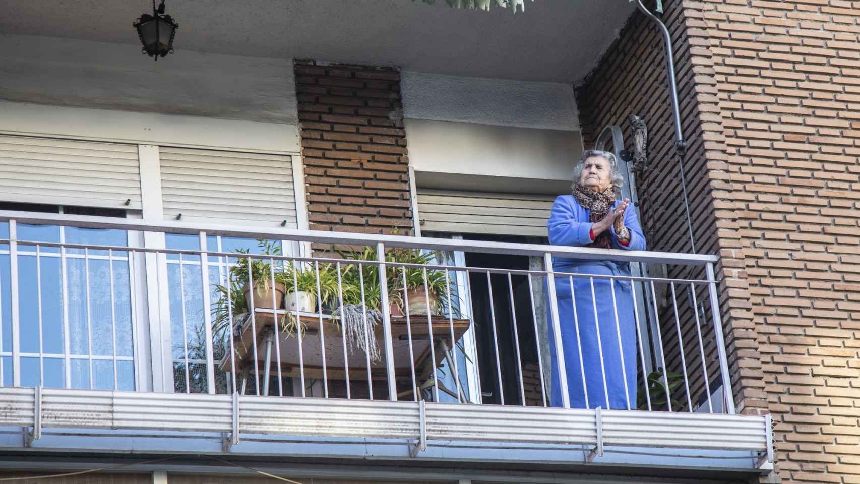 Una mujer aplaude desde su balcón a los sanitarios.