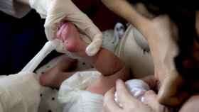 Una matrona realiza la prueba del talón a un bebé