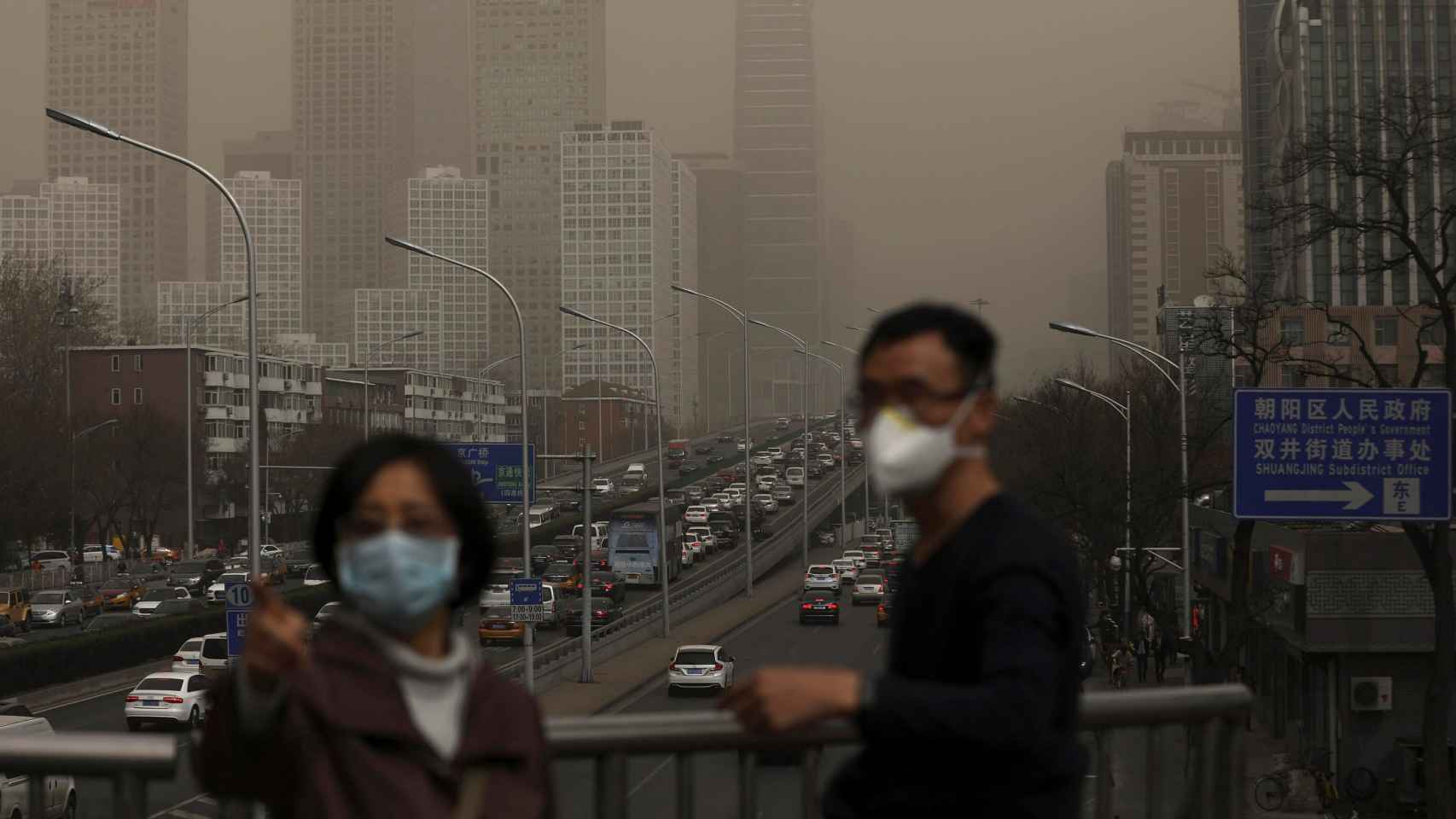 Un hombre y una mujer se protegen con máscaras de la nube de contaminación que cubre la ciudad de Pekín (China).