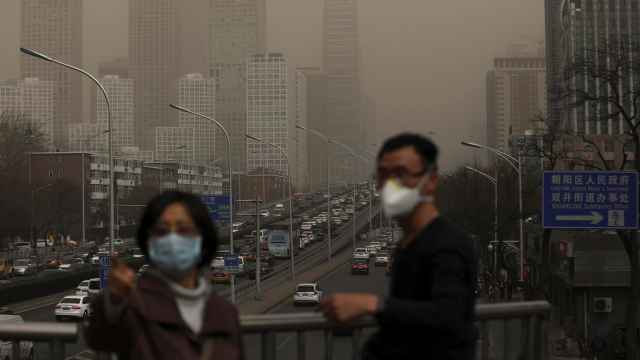 Un hombre y una mujer se protegen con máscaras de la nube de contaminación que cubre la ciudad de Pekín (China).