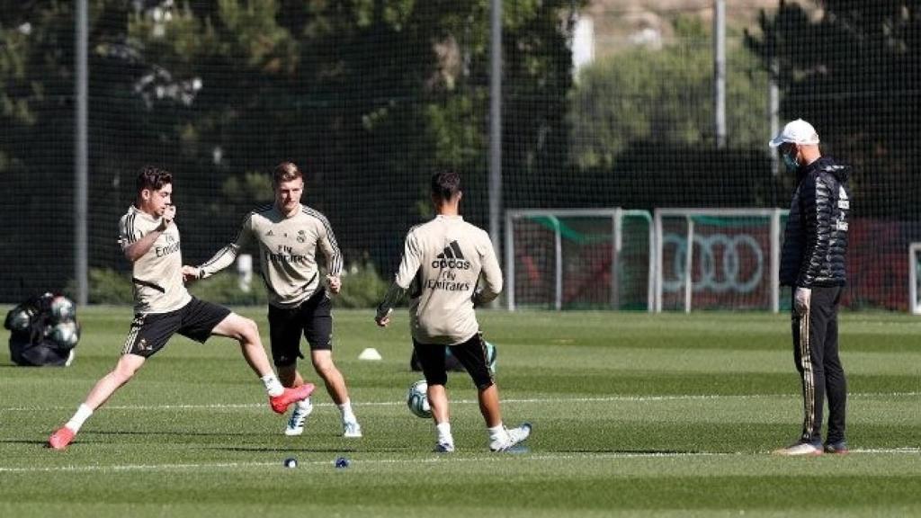 Fede Valverde, Toni Kroos y Marco Asensio disputan un balón bajo la mirada de Zidane