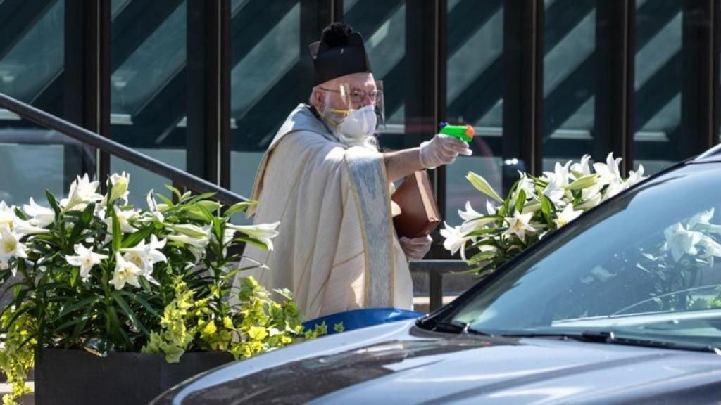 El padre Tim Pelc bendice a los fieles que se encuentran dentro del coche.