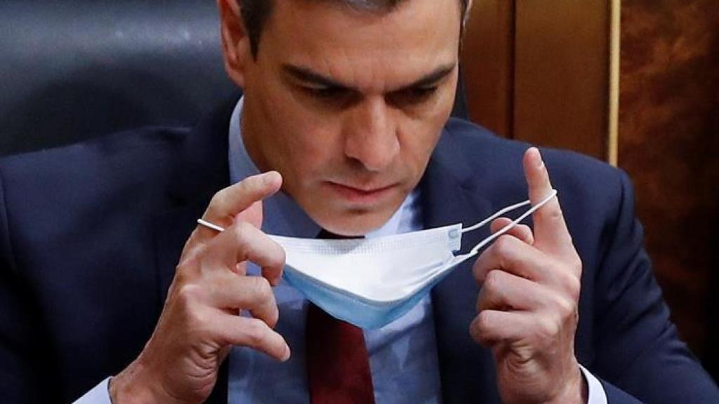 Pedro Sánchez en su escaño del Congreso colocándose la mascarilla.