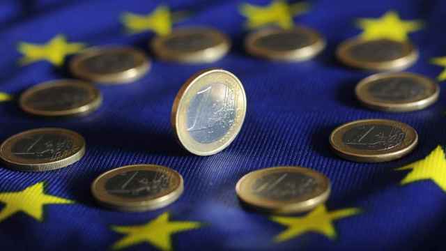 Monedas de euro sobre la bandera de la Unión Europea.