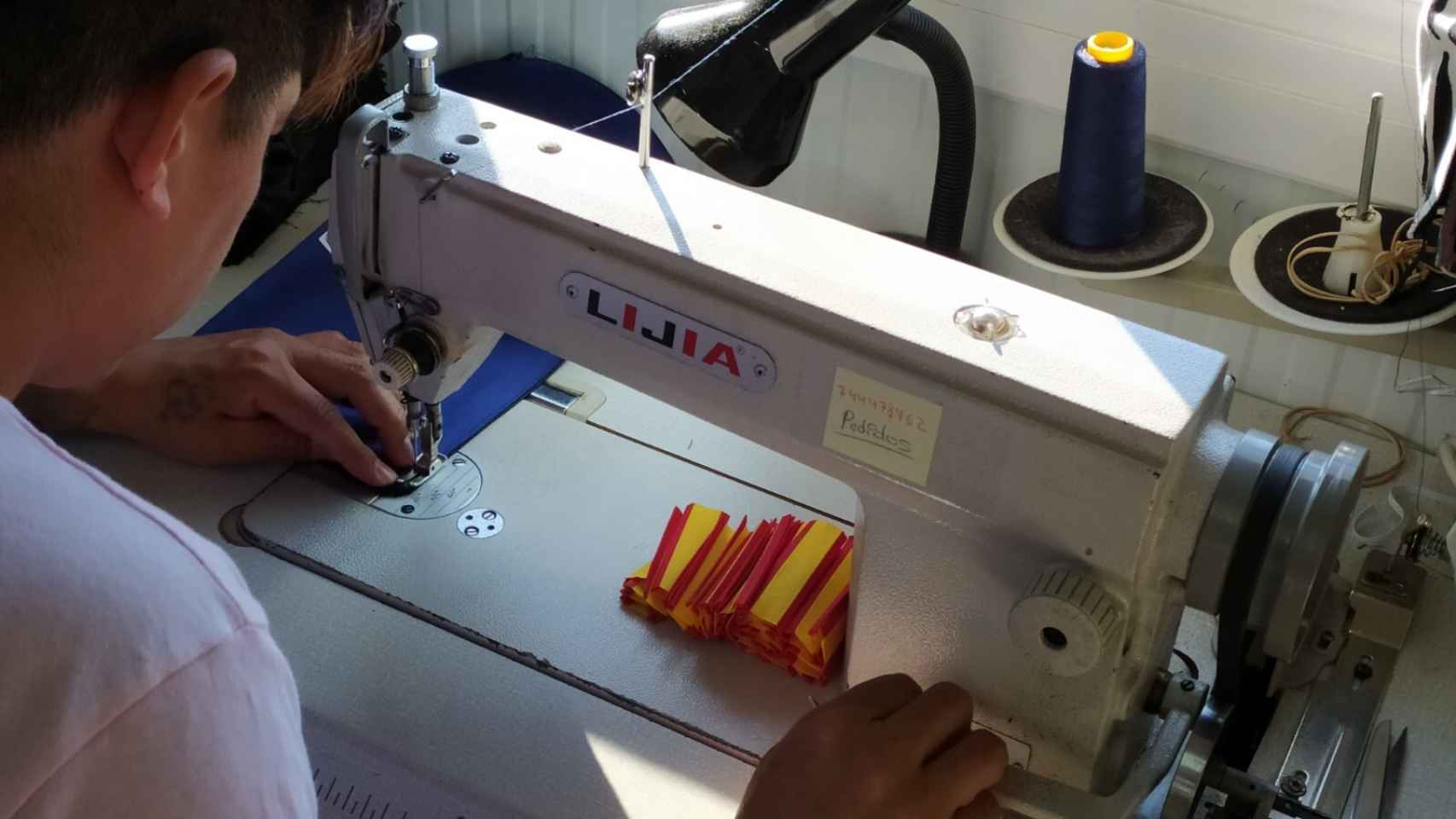 Un empleado confeccionando las banderas españolas en la mascarilla.