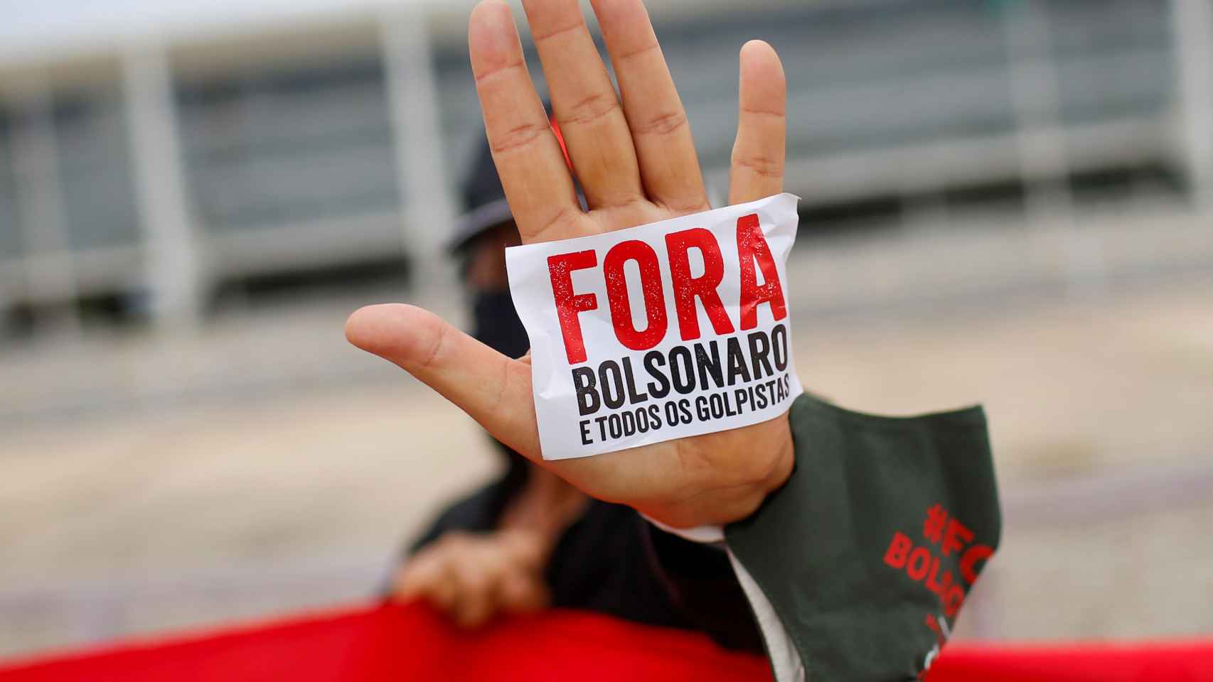 Un manifestante muestra una pegatina en la que se puede leer 'Bolsonaro,  fuera', durante una protesta en Brasilia.