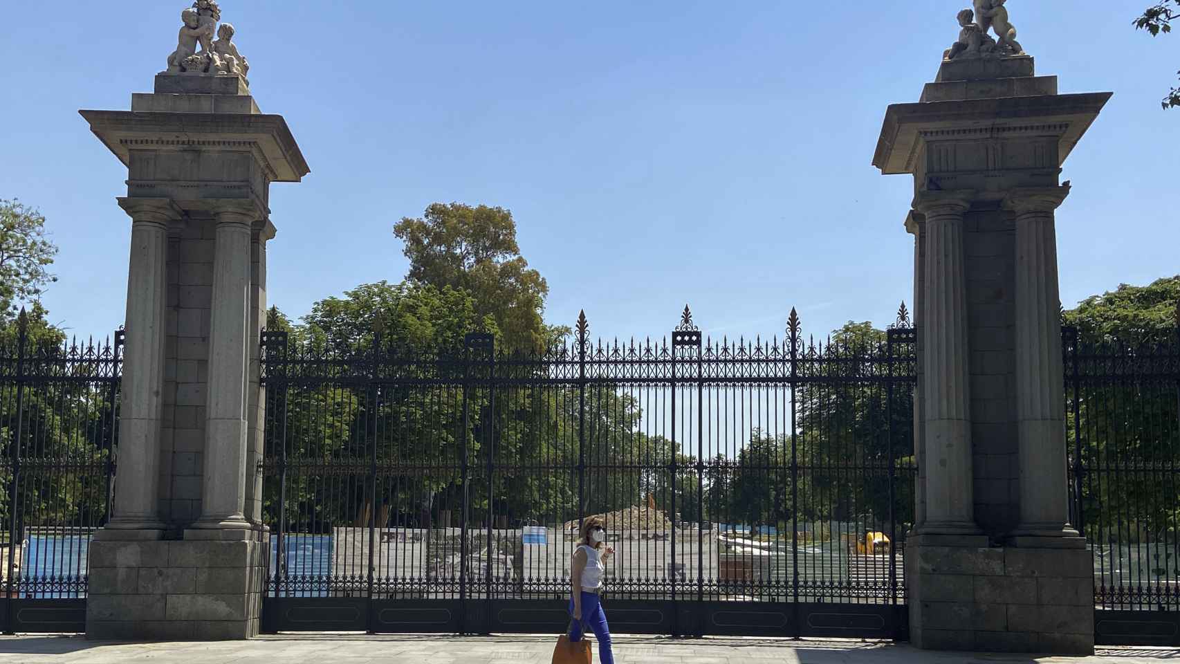 Una mujer pasa al lado de una de las puertas del parque de El Retiro.