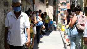 Decenas de personas hace cola para recibir comida de organizaciones caritativas en Carapita, Caracas.