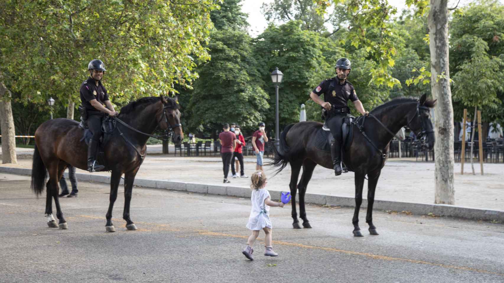 Una niña junto a policías a caballo, este lunes en el Parque del Retiro.