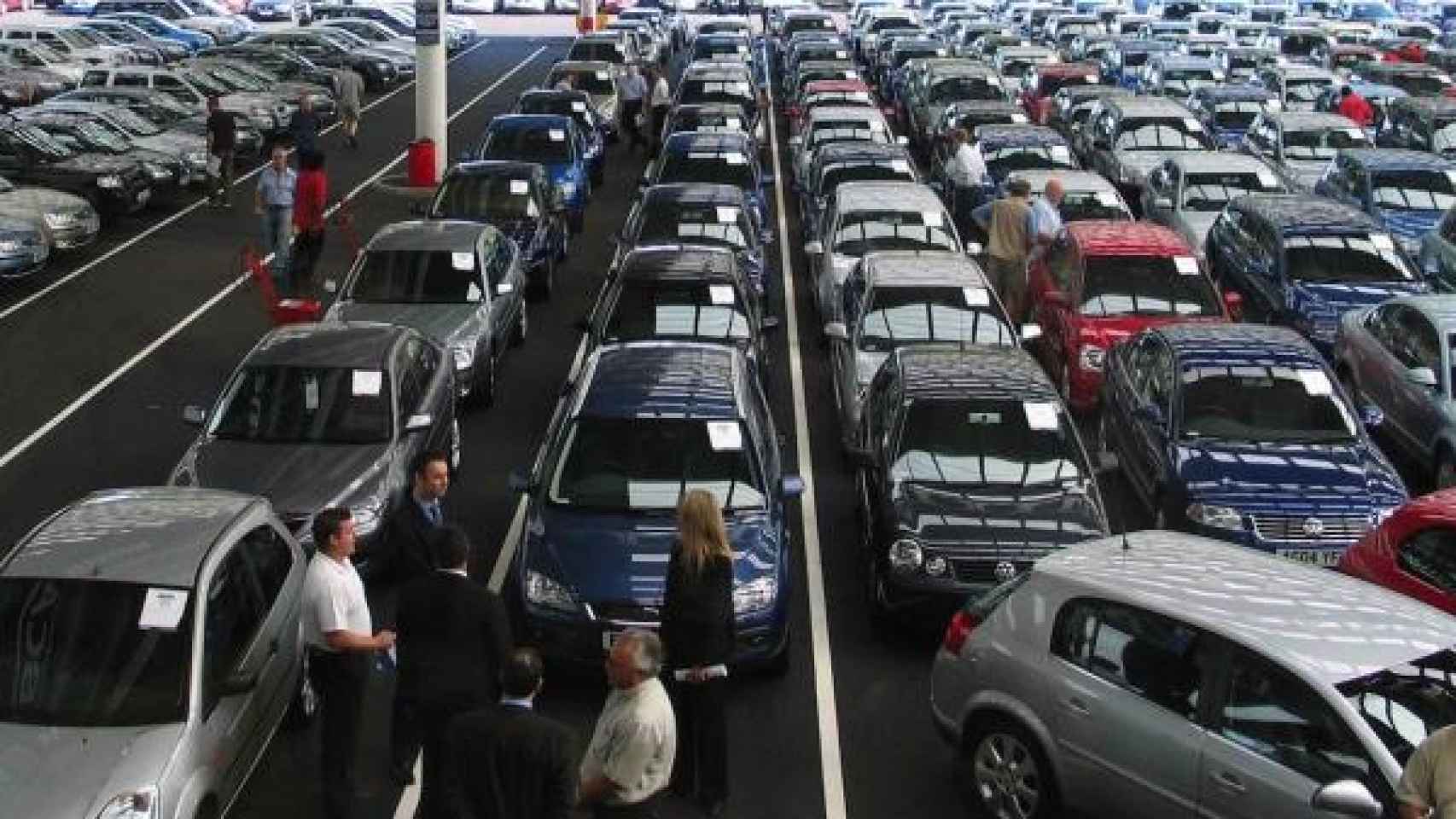 Un grupo de personas observando coches en concesionario.