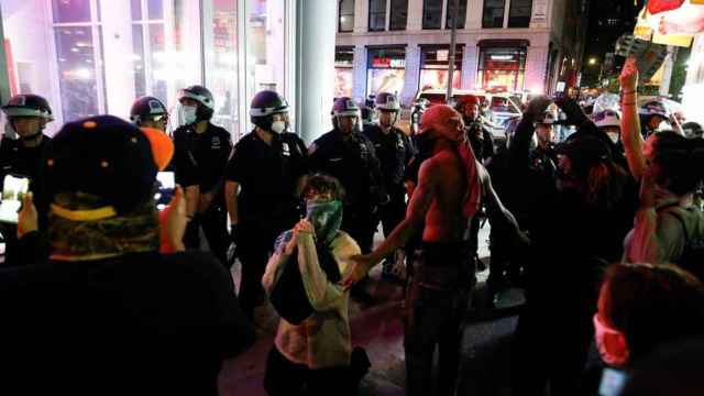 Un manifestante se arrodilla frente a la Policía en Nueva York.