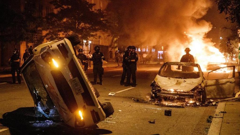 Agentes de policía tras dos coches incendiados en Washinton.