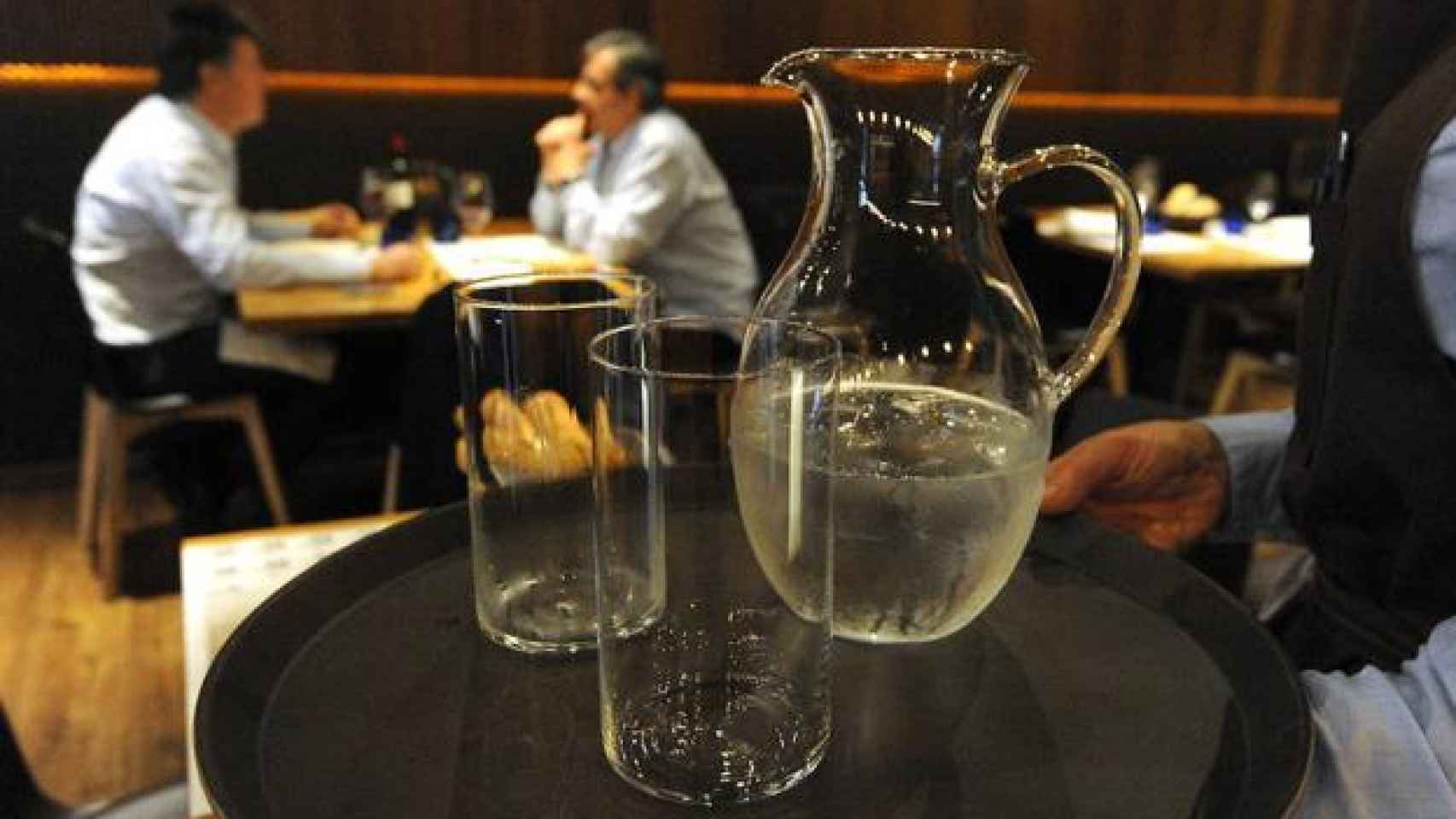 Un camarero con vasos de agua.