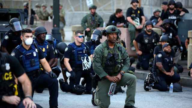 Oficiales se arrodillan con los manifestantes durante una protesta en Atlanta.