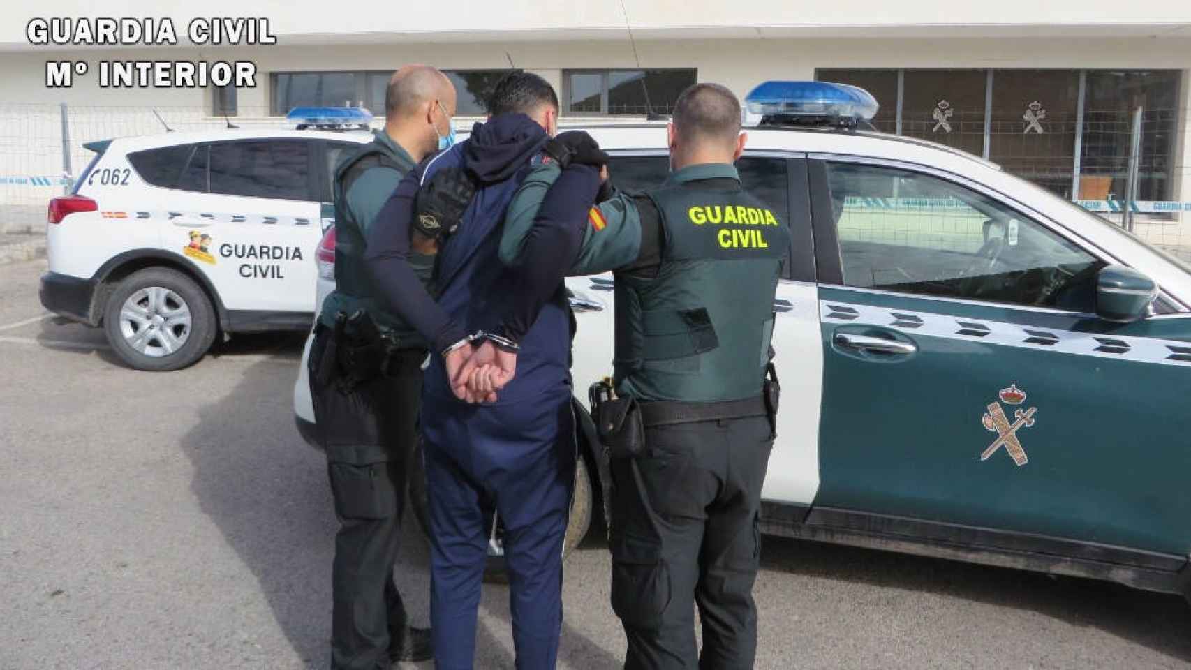 Dos agentes de la Guardia Civil con uno de los detenidos