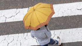 Una persona cruzando con un paraguas.