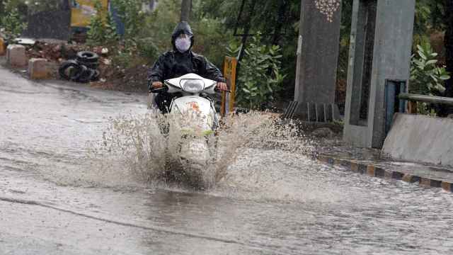 Una motocicleta atraviesa una balsa de agua tras las lluvias torrenciales. EFE/EPA Sanjeev Gupta