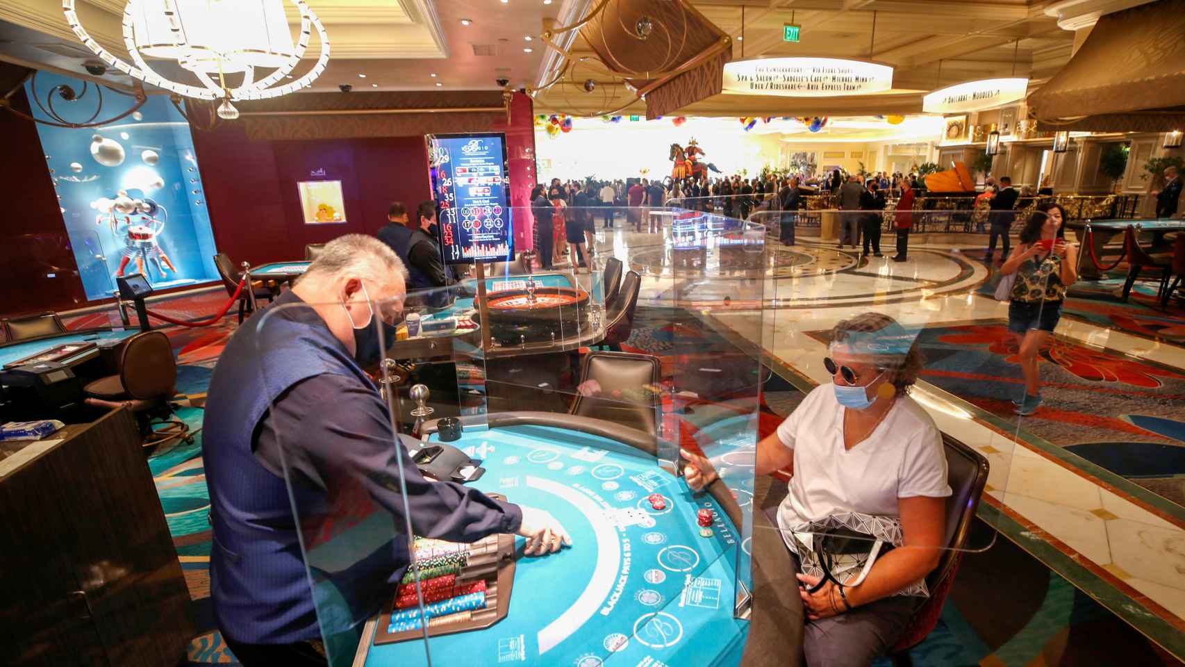 Una mujer juega al blackjack con una mampara que la separa del crupier en el Hotel-Casino Bellagio.