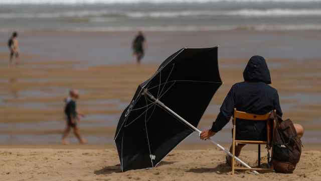 Un joven se protege este sábado con un parasol en la playa de la Zurriola de San Sebastián.