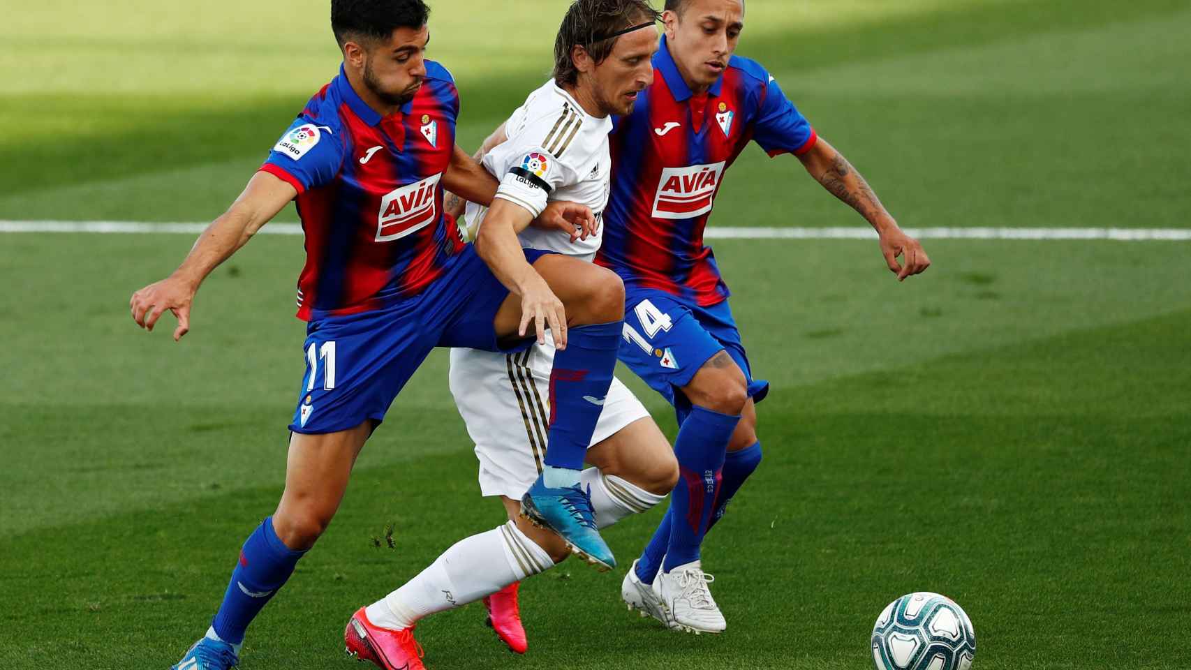 Dos jugadores del Eibar intentan robar el balón a Luka Modric