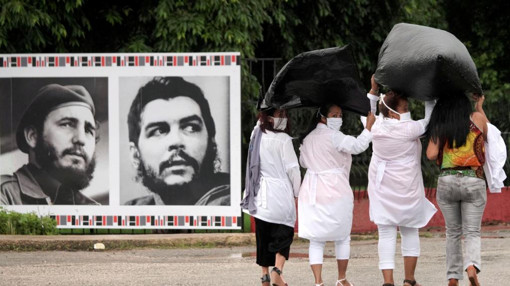 Unas médicas pasan junto a unas fotografías de Fidel Castro y el Che Guevara en la Havana.