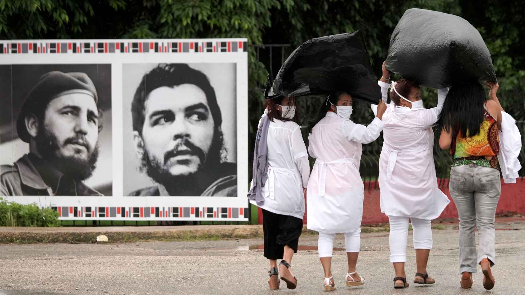 Unas médicas pasan junto a unas fotografías de Fidel Castro y el Che Guevara en la Havana.
