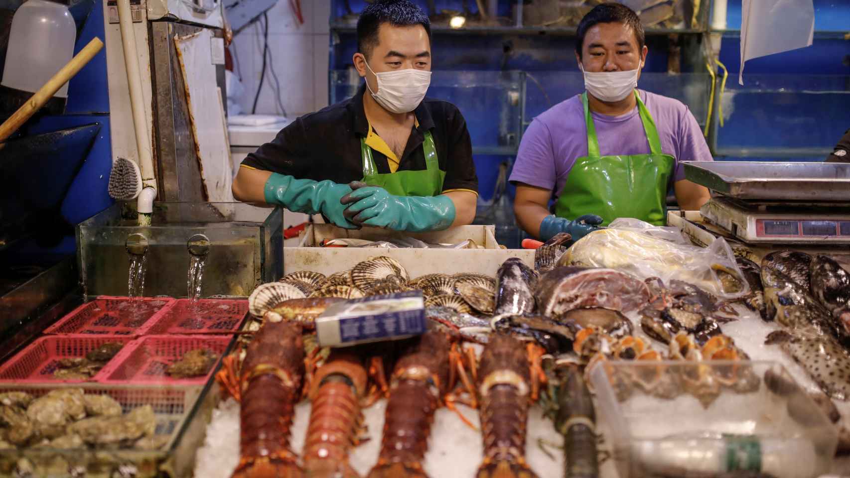 Vendedores de pescado con mascarilla en un mercado de Pekín