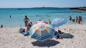Varias personas este domingo en el primer día de la nueva normalidad en la playa de Punta Prima, Menorca.