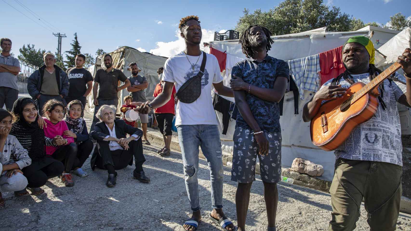 Refugiados tocan la guitarra y cantan en el campo de Moria.