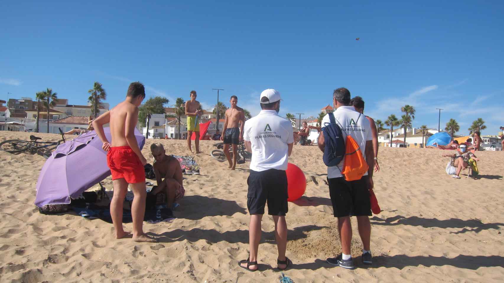 Los vigilantes de la playa recomiendan a unos jóvenes que no jueguen con la pelota.