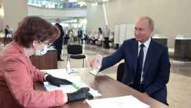 El presidente ruso, Vladimir Putin, muestra su pasaporte al acudir a votar en el referéndum.