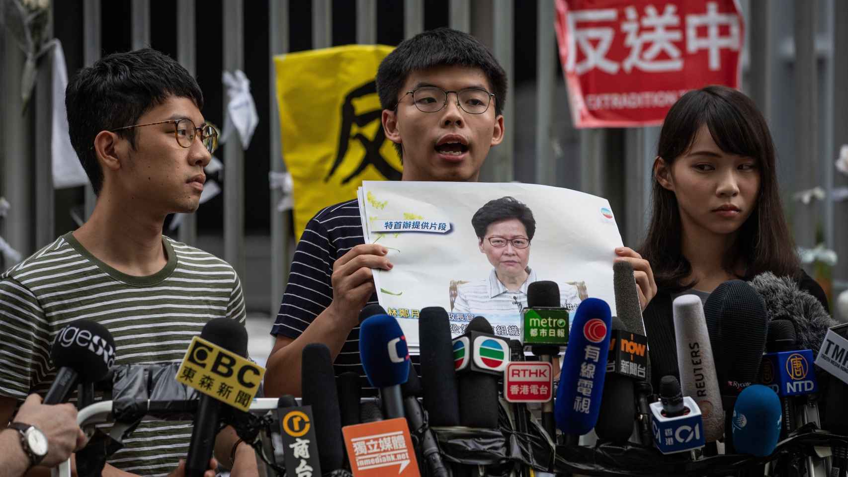 Los activistas en favor de la democracia Nathan Law (izqda), Joshua Wong (centro) y Agnes Chow (dcha) en rueda de prensa frente al edificio del Consejo Legislativo en Hong Kong.