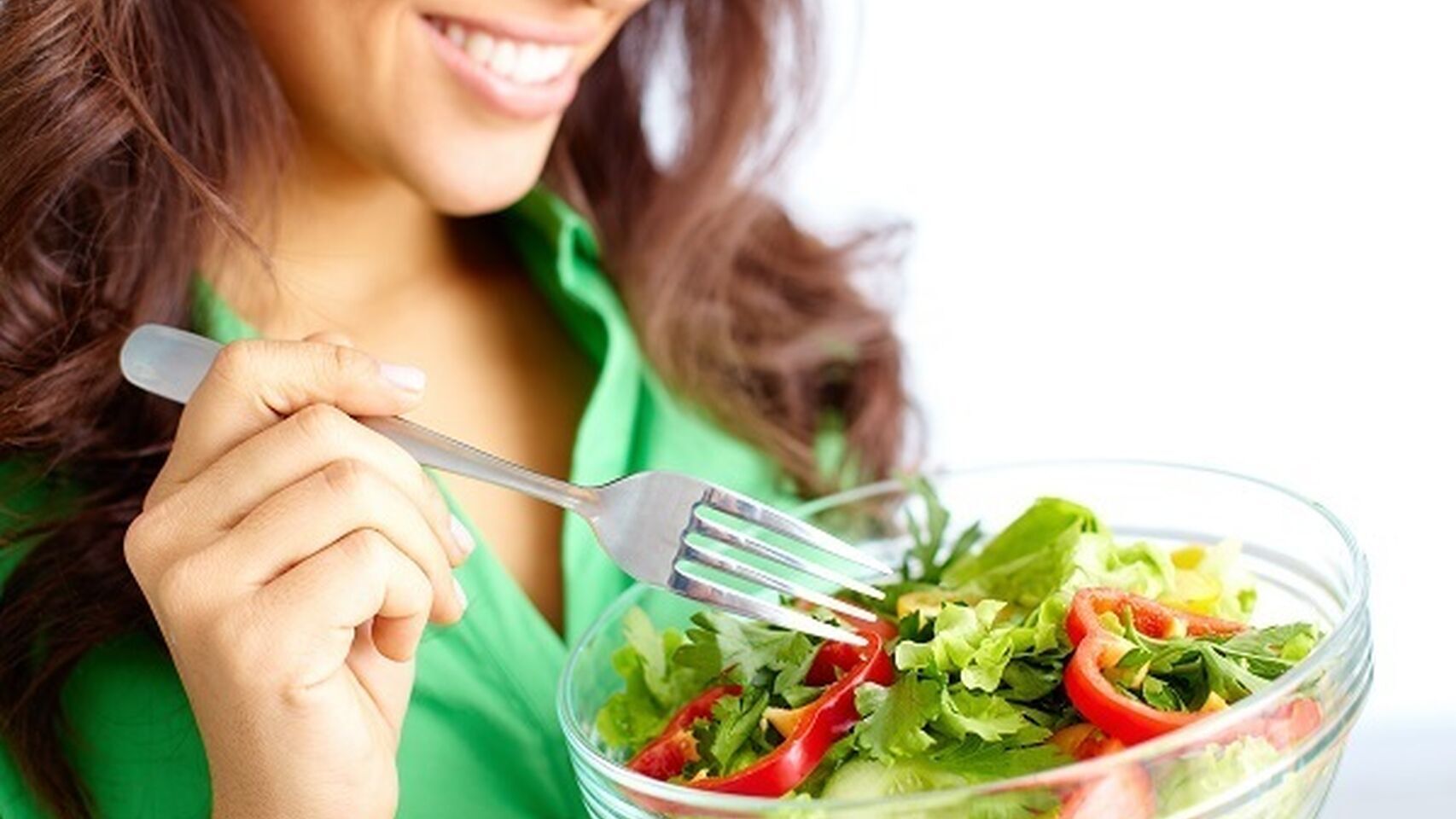 Una mujer disfruta de una ensalada verde.