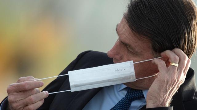 El presidente de Brasil, Jair Bolsonaro, se pone una mascarilla.