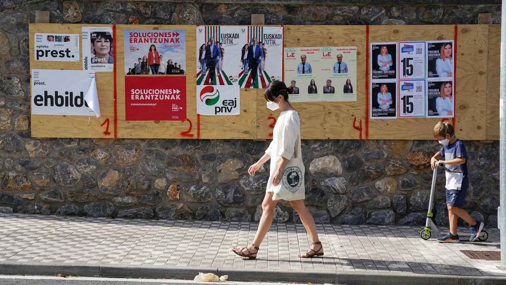 Una mujer camina frente a unos carteles electorales en la localidad de Ordizia.