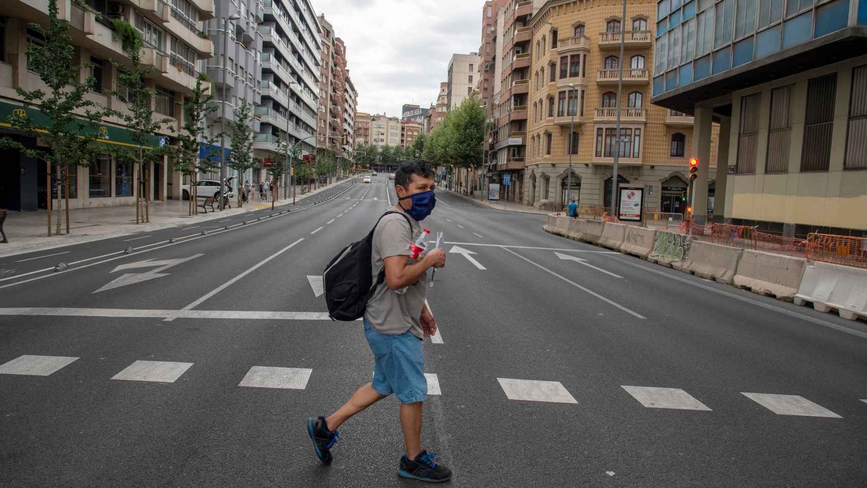 Un vecino cruza la calle en una avenida de Cataluña prácticamente vacía.