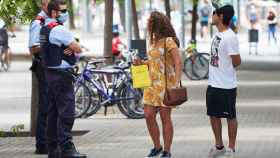 Mossos informan a una joven pareja de la obligatoriedad de la mascarilla en Barcelona. EFE/ Alejandro García