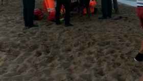 Personal sanitario asistiendo sobre la arena a uno de los rescatados