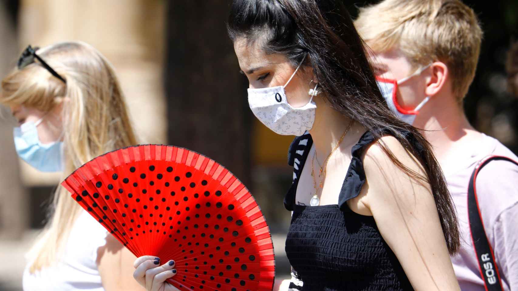 Varias mujeres con mascarillas y abanico caminan esta semana por una calle de Córdoba.