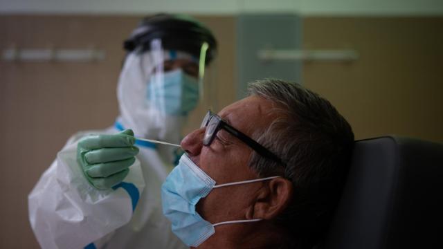 Una profesional sanitaria realiza una prueba PCR a un paciente en el CAP Raval Nord de Barcelona.